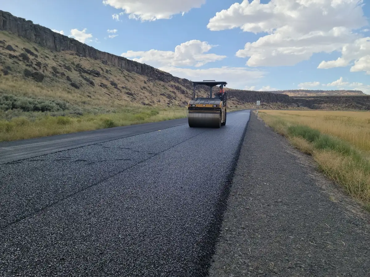 Steel drum road roller compacting fresh asphalt